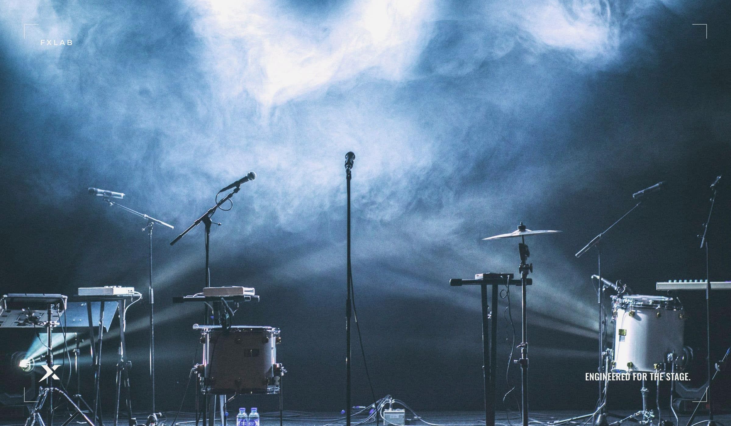 Beams of light cutting through haze over an empty concert stage